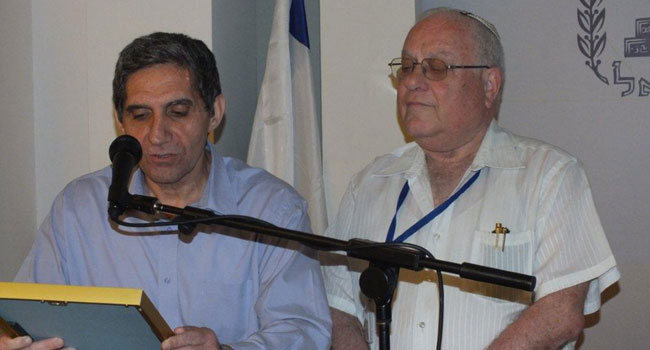 משה זעירא מודה ללנדאו על שנות שירותו הארוכות, הפוריות והיצירתיות, ועומד להעניק לו את המגן ולנדאו על המשמר מאזין ומציץ מאחוריו