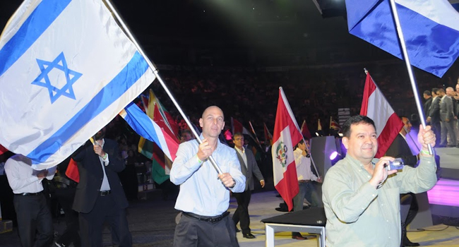 שמוליק בר נושא ומנופף בדגל ישראל בדרך לעלייה על הבמה בפתיחת מליאת היום השני של כנס השותפים העולמי WPC 2012 הנערך השנה בטורונטו. צילום: פלי הנמר
