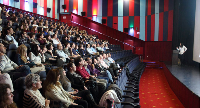 עובדי מידעטק מקשיבים להרצאתה של מנכ"לית החברה חנה שראל, לפני תחילת הסרט 