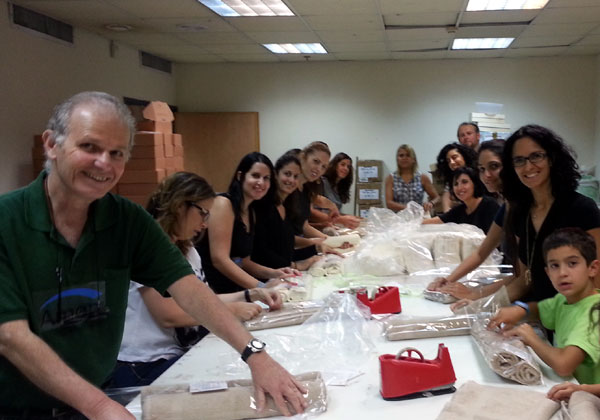 עובדים בקבוצת אמן אורזים חבילות לחג בבית איזי שפירא. מימין: עובדי אמן מיכל ראובן וילדיה, ורד חורי, שרית שבתאי, בת מירז לביא, מיכאל אוסצ'ב, בטי נגר, מיטל רוזמן, אסנת מירל, שירלי מדר, דקלה טובה, מיכל לב ואלישע יואלי