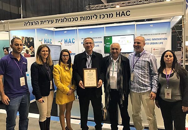 מימין: שירה לביא, מנהלת מרכז הצעירים של עיריית הרצלליה; שלומי אשכנזי, מייסד greenq; יהודה בן עזרא, מנכ"ל העירייה; משה פדלון, ראש העיר; מיה כץ סגנית וממלאת מקום ראש עיריית הרצליה; איריס ארבל גנץ, מנהלת HAC; ועומרי כהן, בוגר האקסלרטור. צילום: יח"צ HAC