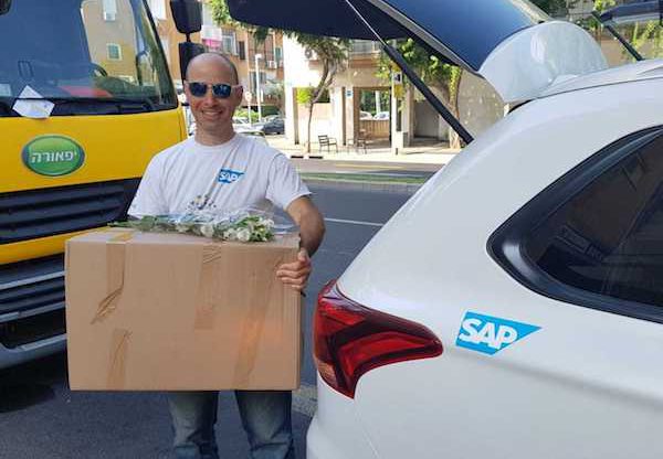 אסף אורטנר, מנהל פרויקטים בסאפ ישראל בדרך עם חבילת המזון ופרחים לחג. צילום: יח"צ