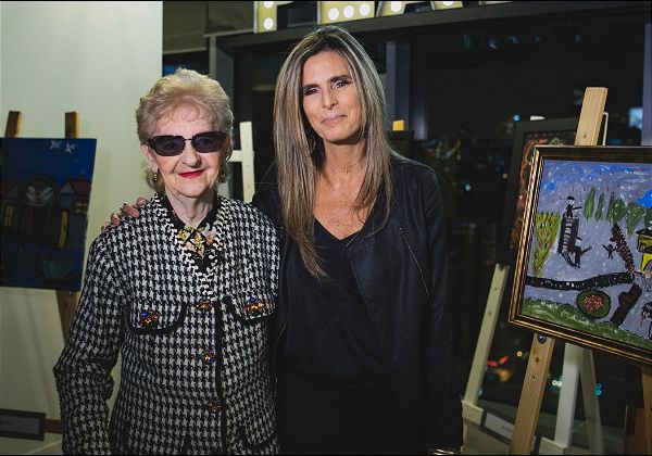 עדי סוֹפר-תאני, מנכ"לית פייסבוק ישראל, עם ז'ני רוזנשטיין, ניצולת שואה בת 84, בתערוכה של ציוריה במשרדי פייסבוק ישראל. צילום: ויקטור לוי