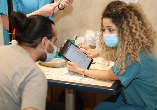 אחות מסבירה לאחד המתחסנים על תהליך החיסון באמצעות האפליקציה. צילום: דוברות בית החולים רמב"ם