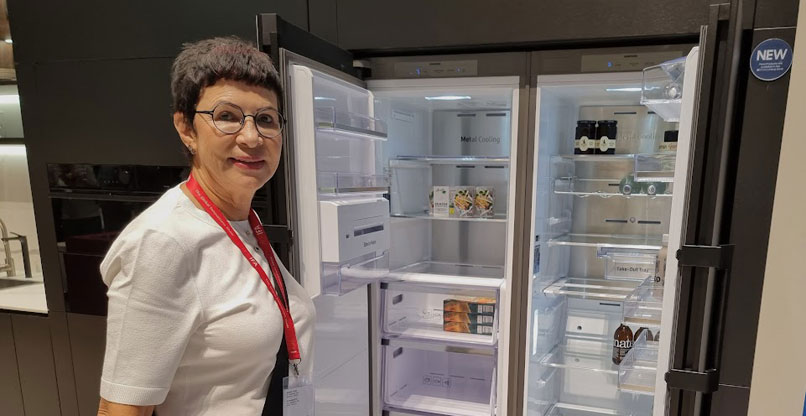 דליה אסיא-פלד לצד מקרר חכם של סמסונג, שגם הוא מבוסס על בינה מלאכותית.