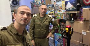 אורון מנחה ומיכה בלכמן, עובדי חברת אורקל, קצינים בתפקידים בכירים בשירות מילואים פעיל וחובבי לגו, שהקימו את המיזם, על רקע ערימות של ערכות לגו.