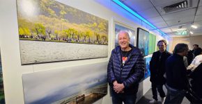 משה אלון בתערוכה, ליד אחת התמונות שצילם.