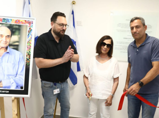 גזירת הסרט במרכז החדש בשדרות. מימין: אלון דוידי, ראש עיריית שדרות; רות אסף, אלמנתו של לולו ז"ל ובעלת השליטה בקבוצת אמנת; וארז רחמיל, משנה למנכ"ל והממונה על חטיבת הטכנולוגיה והמחשוב בבנק הפועלים. ברקע: תמונתו של אברהם (לולו) אסף ז"ל.
